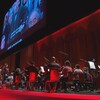 Un orchestre est devant un écran de cinéma.