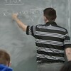 Un enseignant de mathématiques dans une salle de classe du secondaire.
