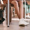 Des jambes d'élèves assis à leur pupitre et leurs sacs posés par terre dans une salle de classe.
