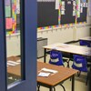 La vue d'une classe vide par une porte entrouverte.