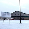 Un bâtiment de type entrepôt en hiver, avec une affiche jaune sur laquelle « Dépistage covid sans rendez-vous » est écrit.