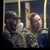 Deux hommes et une femme en habit de combat dans l'autobus. 