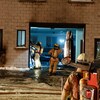 Des pompiers sont à l'oeuvre autour de la porte de garage d'un commerce incendié.