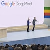 Deux hommes sont accueillis sur scène, lors d'une présentation de Google en plein air. 