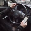 Un conducteur de voiture tient son téléphone cellulaire en conduisant.
