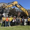Des élus et des travailleurs de la construction posent devant une excavatrice.
