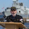 Craig Baines parle aux médias devant un navire de la marine canadienne.