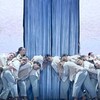 Des danseurs sont penchés vers un immense livre fermé. 