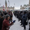 Un groupe de manifestants invectivent des policiers à Ottawa l'hiver.