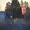 Un camion dépasse un drapeau du Canada suspendu au-dessus de l'autoroute.