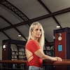 Une femme pose dans une bibliothèque.