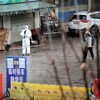 Un homme vêtu d'un habit de protection contre la contamination se tient debout dans le marché fermé.