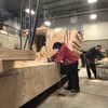 Des gens travaillent sur des morceaux de bois dans un hangar. 