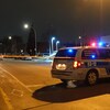 Un véhicule de police dans une rue de Montréal, phares allumés, derrière un ruban policier.