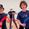 Trois jeunes tiennent des bâtons de hockey.