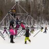 Des enfants en habit de neige jouent dans un module. 