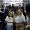 Deux jeunes filles souriantes au milieu d'une foule dans le hall d'entrée d'une cour de justice.