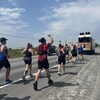 Une vingtaine de coureurs suivent un aotobus.