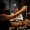 Une serveuse verse une bière dans un verre dans un bar.