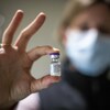 Une personne tient une fiole de vaccin.
