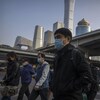 Des personnes portant un masque de protection marchent dans une rue, en Chine.