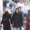 Des personnes masquées déambulent dans un marché décoré pour Noël.