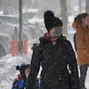 Une femme masquée marche sur un trottoir du centre-ville de Rimouski accompagnée d'un petit garçon.