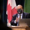 Le Dr Saqib Shahab parle, et porte un masque, devant le drapeau du Canada.