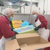 Des travailleurs dans une usine de transformation de fruits de mer s’activent à la tâche. 