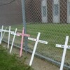 Des croix en bois posées contre le grillage d'une prison.