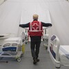 Un employé de la Croix-Rouge vu de dos dans une chambre avec deux lits.