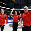 Quatre joueurs de curling célèbrent une victoire. 