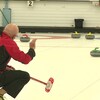 Un joueur de curling analyse la disposition des pierres sur la glace.