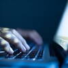 Un homme pose ses mains sur le clavier d'un ordinateur portable dans l'obscurité