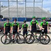 Cinq jeunes cyclistes, en uniforme Subway, prennent la pose pour la caméra avec deux vélos.