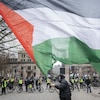 Un manifestant agite un drapeau palestinien devant des policiers.