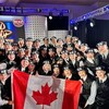 La troupe pose avec le drapeau du Canada sur scène.