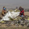 Des secouristes tiennent dans leurs mains des morceaux d'un appareil 737 MAX 8.