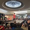 Une femme sur une estrade dans un centre commercial lors d'un défilé de mode.
