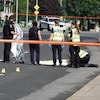 Des policiers auprès d'une victime au sol sur la scène d'un délit de fuite mortel.