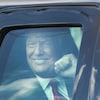 Donald Trump, souriant et le poing levé, vu à travers la vitre d'une voiture à son arrivée à Mar-a-Lago, en Floride.