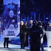 Doris Labonté derrière une bannière hissée en son honneur au centre de la glace du Colisée de Rimouski.