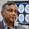 Le Dr Bijoy Menon devant des radiographies d'un cerveau.