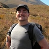 Brian Nadler, lors d'une randonnée en montagne, avec un sac à dos, sourit à la caméra.