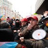 De jeunes hommes avec des porte-voix et des casquettes rouges « Save Canada » copiant le design des casquettes « MAGA »  sont entourés d'autres personnes avec des drapeaux arc-en-ciel.