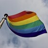 Le drapeau arc-en-ciel flotte au vent.