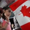 Une petit fille prête serment dans une cérémonie d'octroi de la citoyenneté canadienne, avec un drapeau canadien à l'avant-plan.