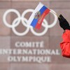 Une femme tient un petit drapeau de la Russie devant les bureaux du Comité international olympique.