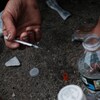 Une personne s'injecte une drogue dans la rue.
