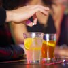 Un homme laisse tomber un comprimé dans un verre, sur un bar.